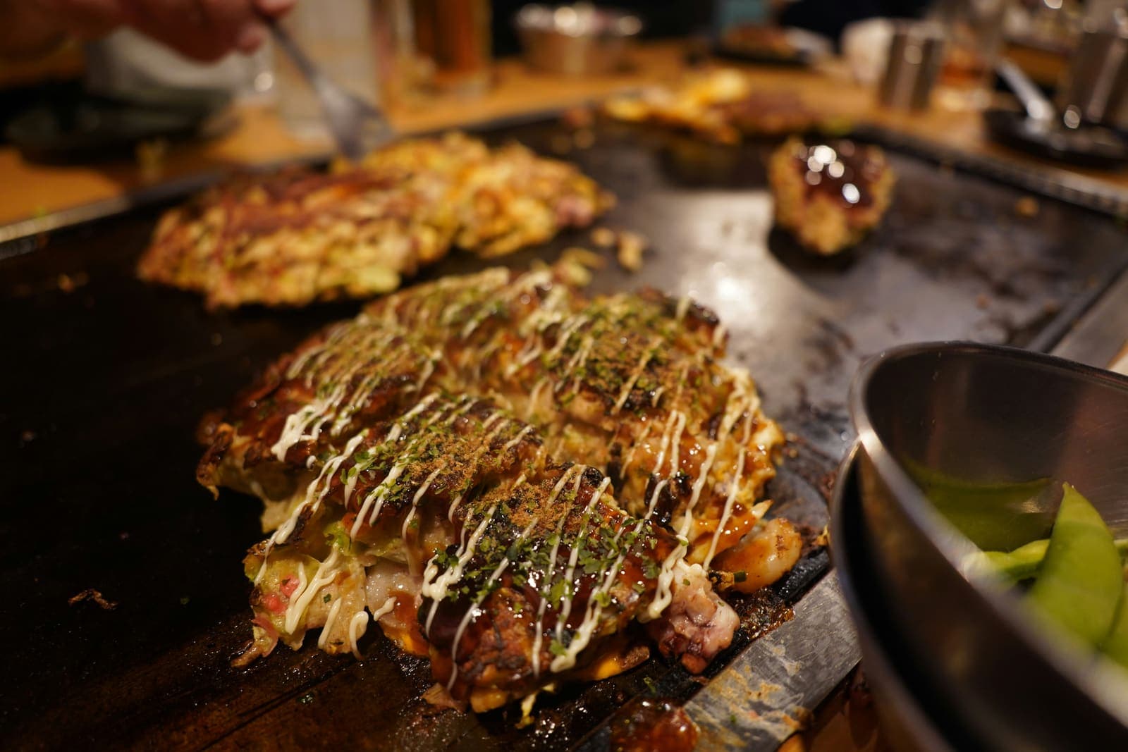 Galette okonomiyaki aux restes de légumes en cuisson sur la plaque, inspirée du Japon